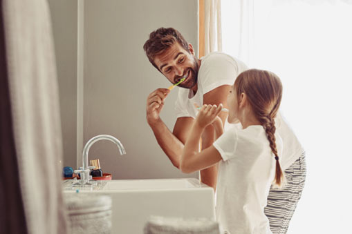 Father and daughter brushing teeth to conserve water