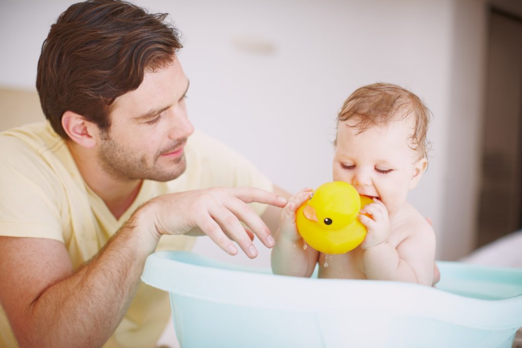 Cleaning bath toys while baby sits in bathtub