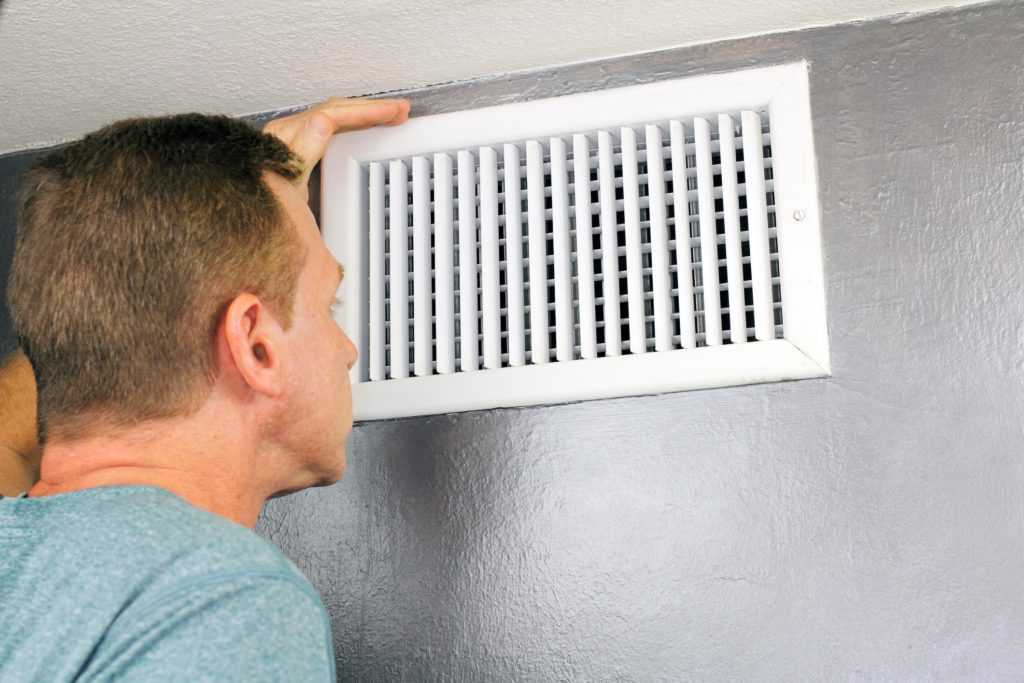 Man inspecting dirty air vent