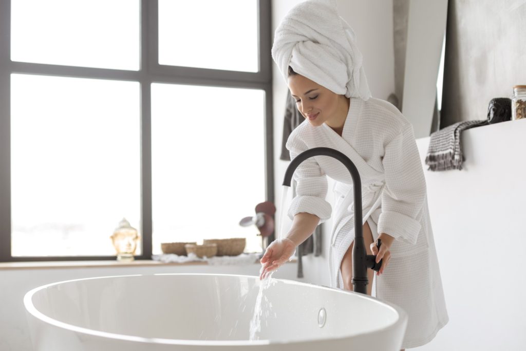 Woman relaxing in a hot bath wearing a towel