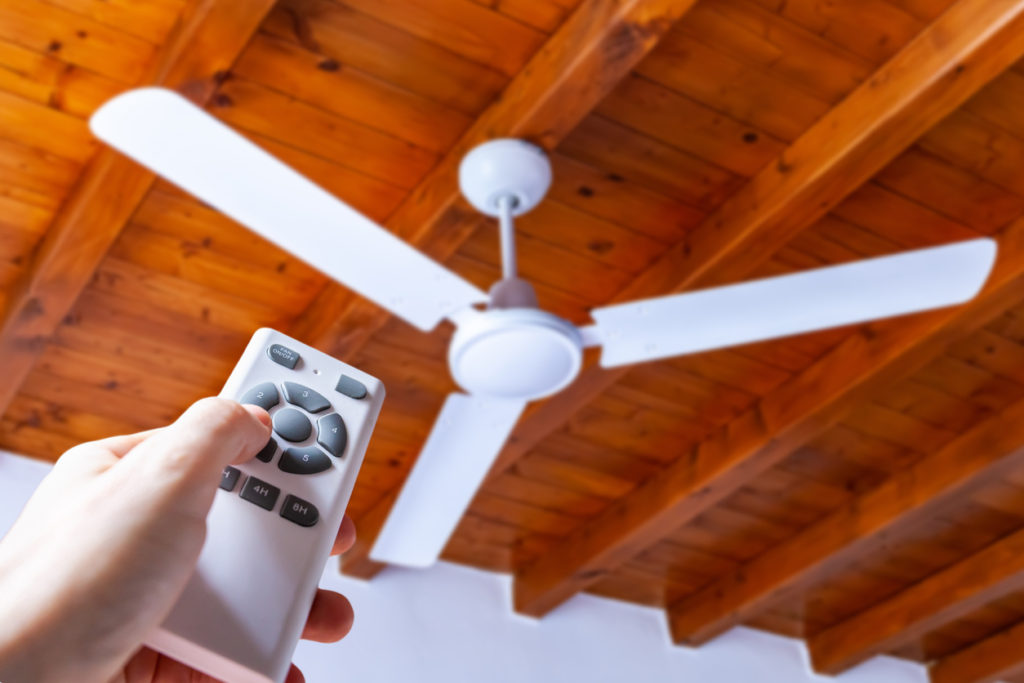 Hand using a remote to operate a ceiling fan