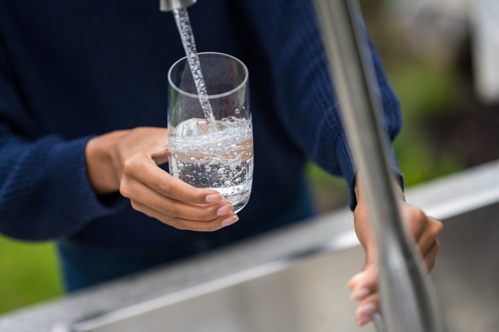 Glass of filtered water pouring from a tap