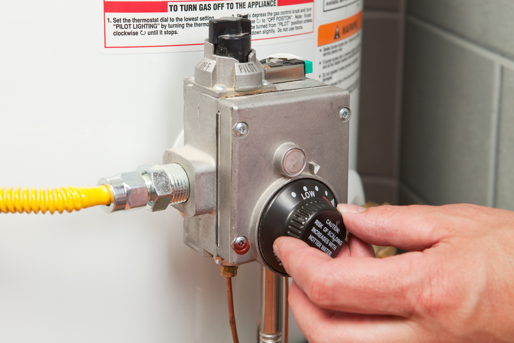 Hand adjusting water heater thermostat