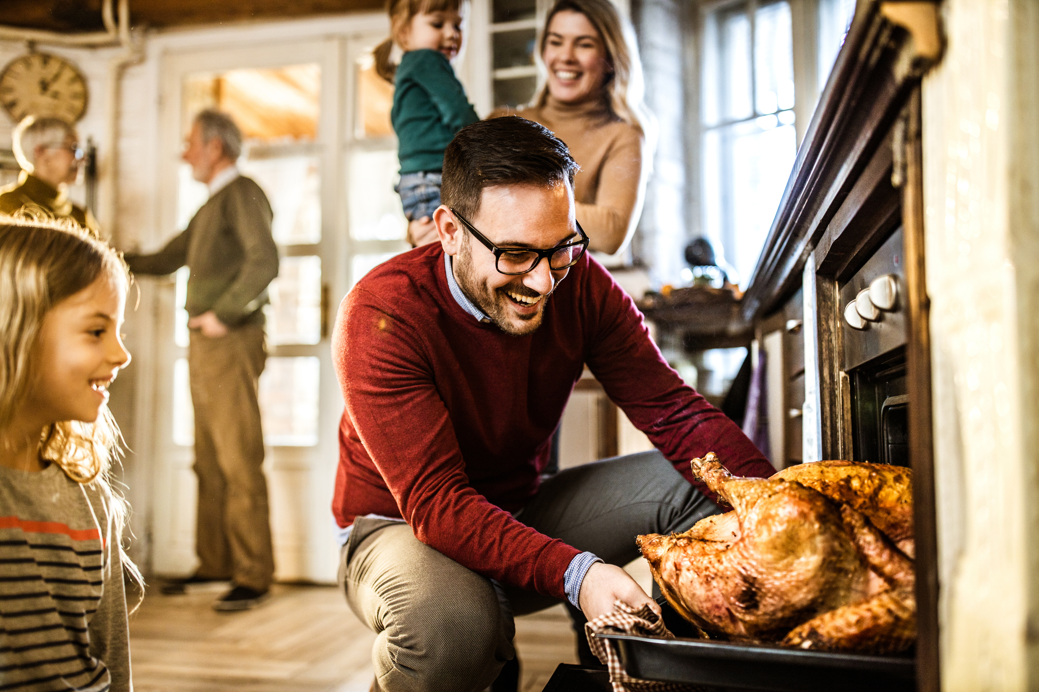 Young man taking Thanksgiving turkey out of oven
