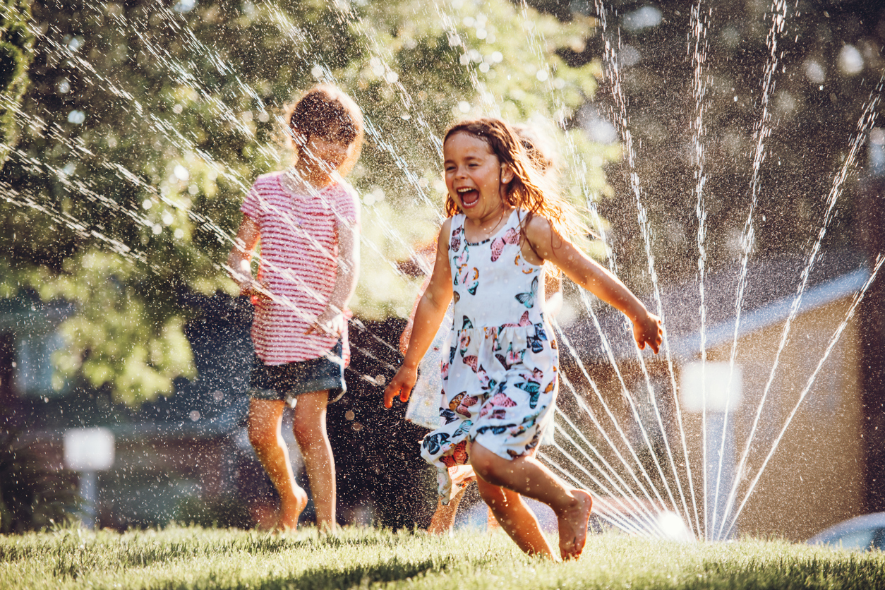 Happy kids playing with garden sprinkler