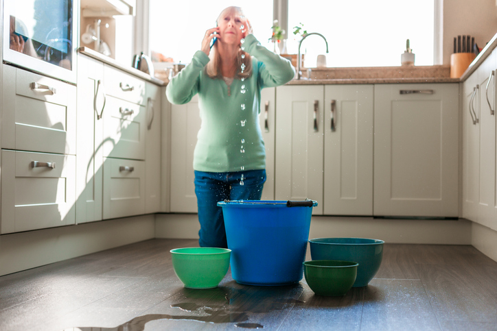 Worried home owner dealing with plumbing emergency water leak in the kitchen