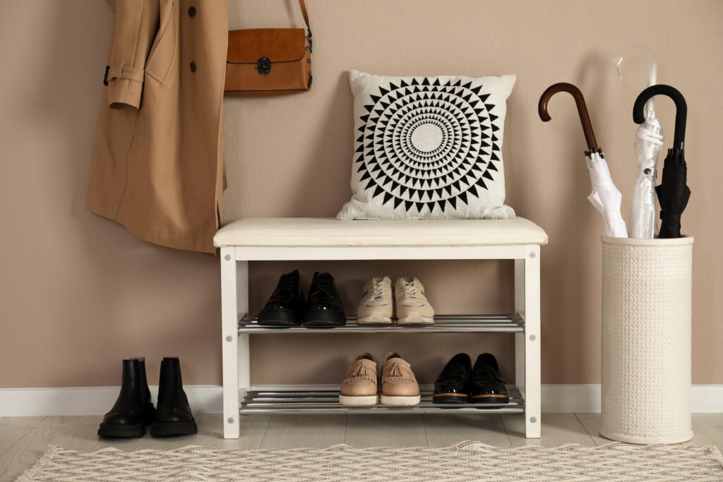 Storage bench with different pairs of shoes near wall in hall