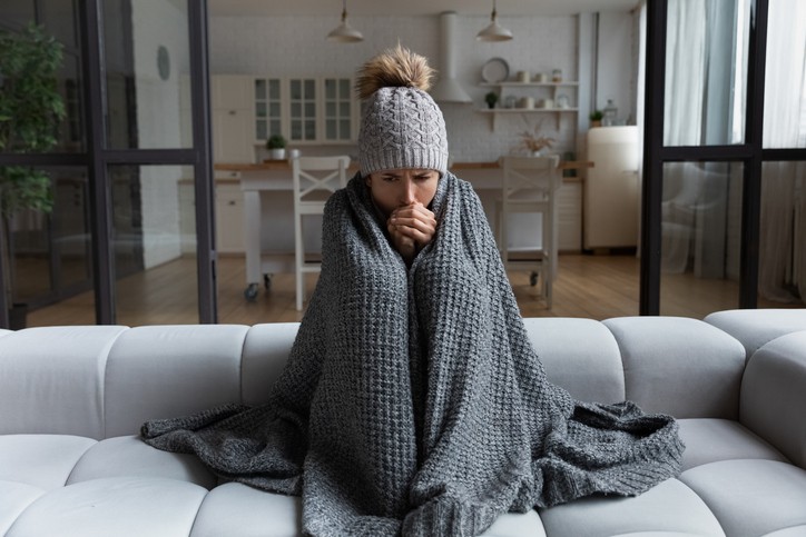 Heating tune-up – Girl wrapped in a woollen shawl feeling cold indoors
